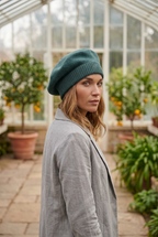 une jeune femme porte un béret en laine qui couvre bien les oreilles de couleur vert bleuté